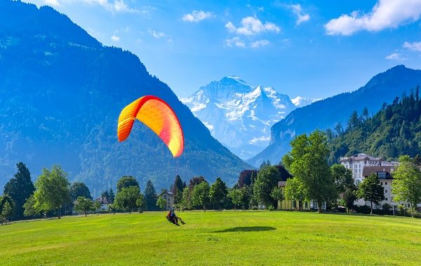 A paraglider landing at Hohematte Park in the center of Interlaken, important tourist center in the Bernese Highlands, Switzerland. The Jungfrau is visible in the background